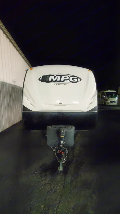 Front view of an MPG Ultra-Lite travel trailer, ideal for an RV rental. Parked at night with a building beside it and another RV in distance.. Cruiser RV MPG Ultra Lite 2017