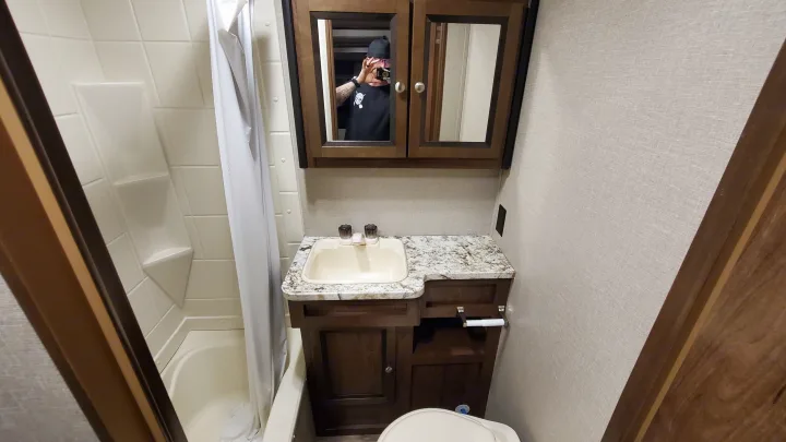 RV rental bathroom showing shower, vanity, sink, toilet, and mirrored cabinet reflecting the person taking the photo.. Cruiser RV MPG Ultra Lite 2017