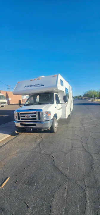 White Majestic rv rental (Class C) parked on cracked asphalt under a clear blue sky.. Thor Majestic 2019
