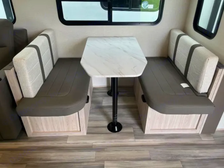 Cozy RV rental dinette features opposing benches with grey seats and light back cushions, plus a marble-look table.. Cruiser RV Essence 2025