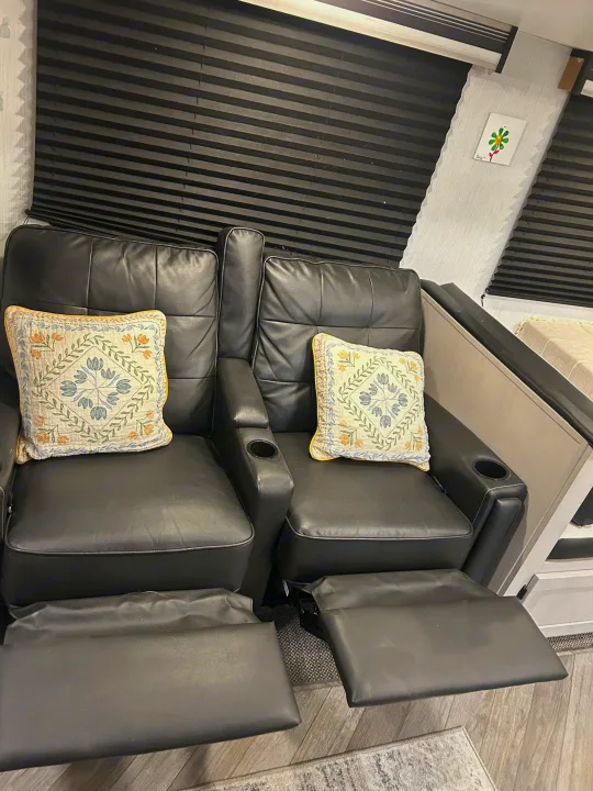 Comfortable black leather recliners with footrests and decorative pillows inside an RV rental. Ideal for relaxing journeys.. Heartland RVs Mallard 2023