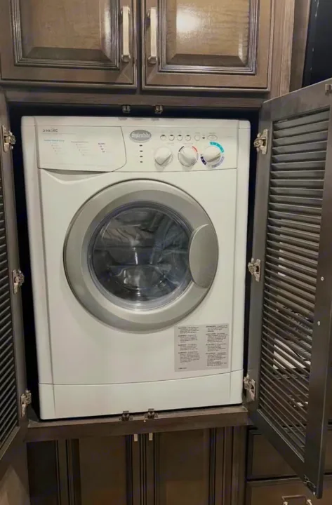 Compact Splendide washer/dryer unit inside dark wood cabinetry, a convenient laundry feature for an RV rental.. Southwind Southwind Motorhome 2020
