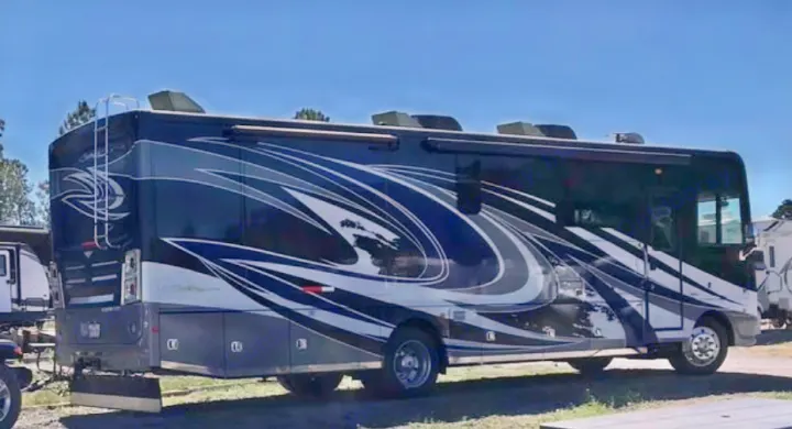 This eye-catching dark blue RV rental motorhome with white/gray swirling graphics, a rear ladder, and roof AC units is a spacious recreational vehicle.. Southwind Southwind Motorhome 2020