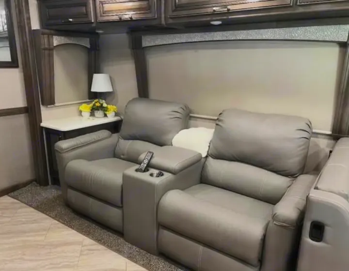 Relax in this RV rental's cozy interior, featuring two grey recliners, a console with cup holders, and a side table with a lamp.. Southwind Southwind Motorhome 2020
