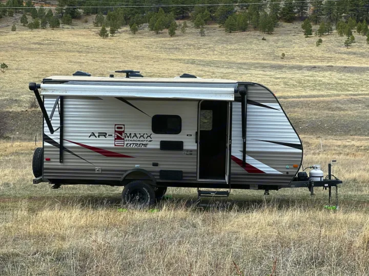 RV rental ready for adventure: Starcraft AR-NMaxx travel trailer parked in a dry grassy field with an extended awning.. Starcraft AR-One Maxx 2017