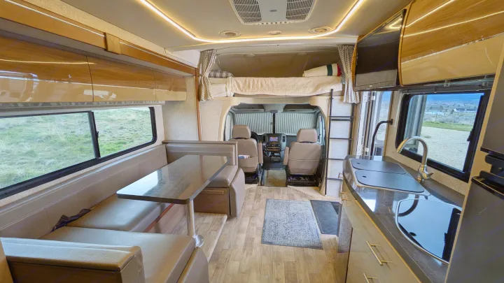 Spacious rv rental interior featuring a dinette, kitchen, and cab-over bed, with bright lighting and scenic window views.. Winnebago View 2017
