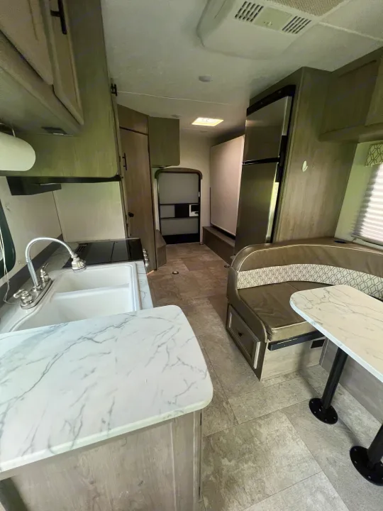 RV rental interior with a bright kitchen featuring a double sink, modern appliances, and a cozy dinette.. Coachmen Freelander 22xg 2020