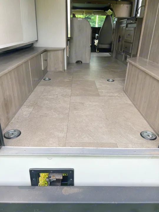 RV rental's versatile interior features light-colored flooring, recessed tie-downs, and wood-paneled storage.. Coachmen Freelander 22xg 2020