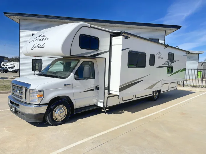 White East to West Entrada RV rental with its slide-out extended, parked on concrete under a clear blue sky.. East to West Entrada 2024