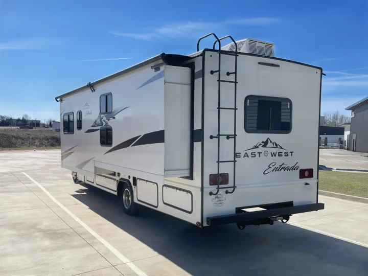 White East West Entrada RV rental, a Class C motorhome with a slide-out extended, parked on concrete under a blue sky.. East to West Entrada 2024