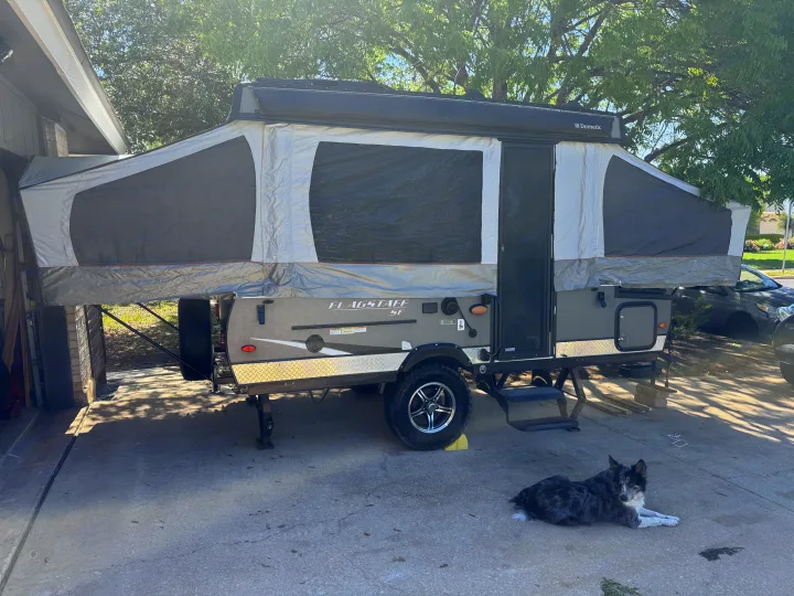 A Flagstaff SE pop-up camper, ideal for an rv rental adventure, fully set up in a sunny driveway with a dog resting nearby.. Forest River Flagstaff 2020