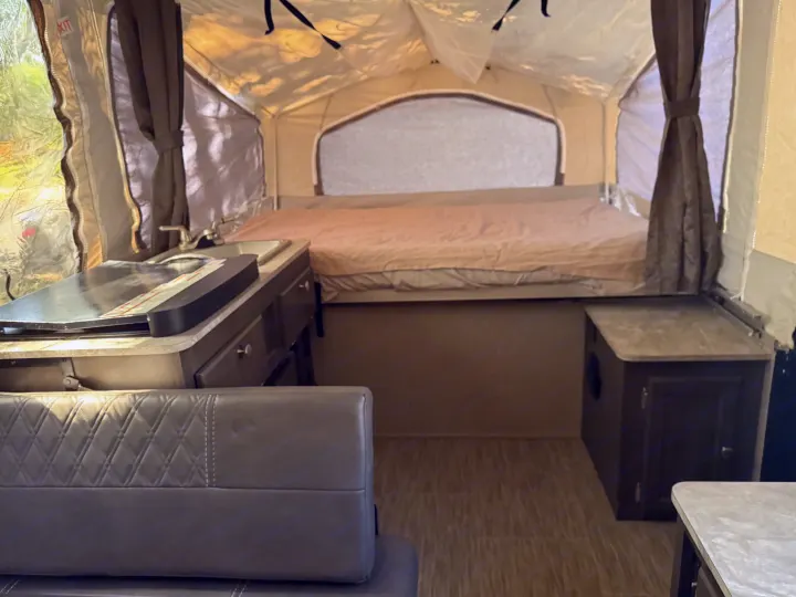 Cozy RV rental interior with a bed, kitchen sink/stove, and seating area for comfortable camping adventures.. Forest River Flagstaff 2020