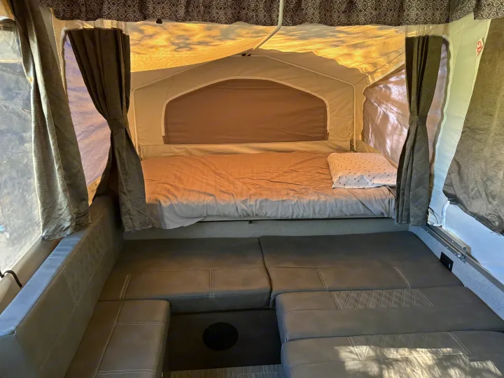 Inside this cozy RV rental pop-up camper: a bed, plush seating, and privacy curtains for comfortable camping adventures.. Forest River Flagstaff 2020