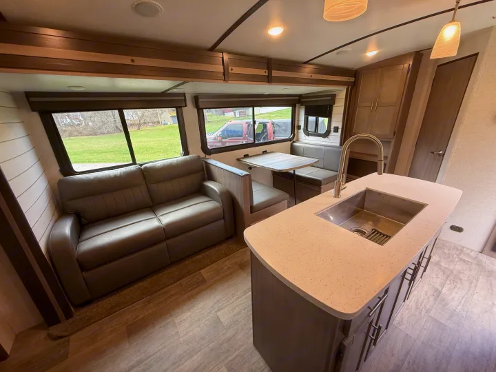 Spacious RV rental interior: modern kitchen island, comfy sofa, and dinette with scenic views. Ideal for travel.. Crossroads RV Sunset Trail 2021