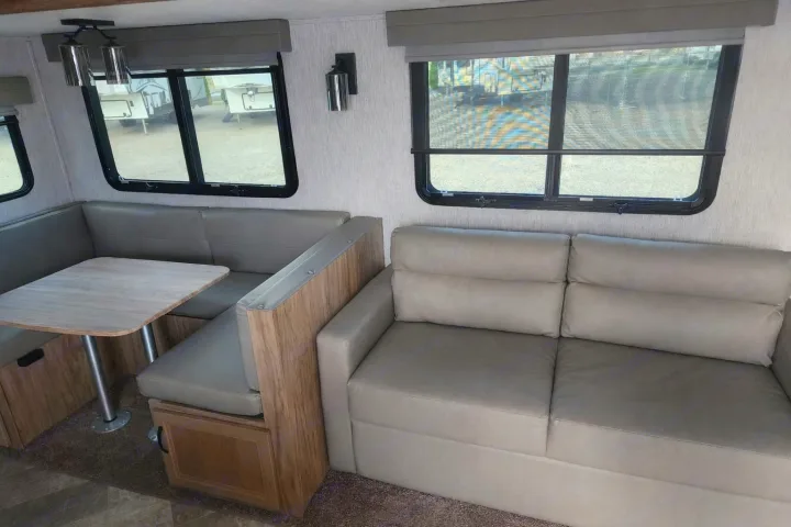 This RV rental interior features a cozy dinette with U-shaped seating and a comfortable sofa, perfect for your next adventure.. Palomino Other 2022