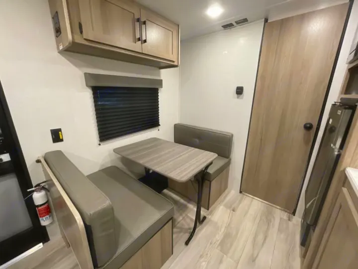 Cozy RV rental dinette with benches, table, and overhead storage. A clean, modern interior for your travels.. Keystone RV Coleman 2025
