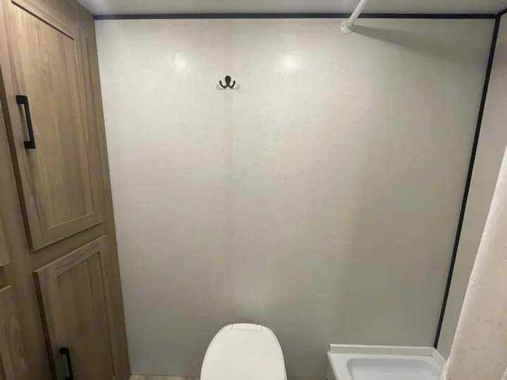 RV rental bathroom with a toilet, wooden cabinet, shower pan, and wall hook, offering practical space.. Keystone RV Coleman 2025