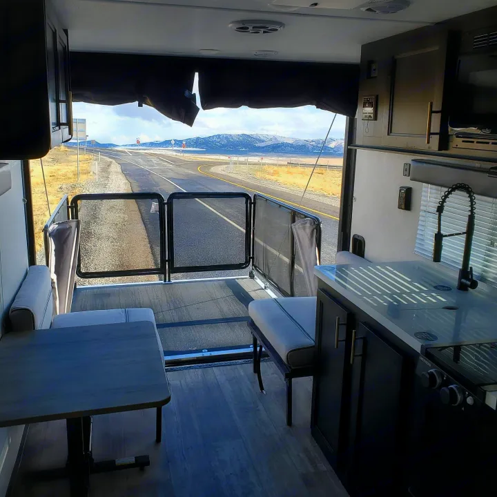 Enjoy an RV rental! Interior shows kitchen, dining, and open ramp with stunning mountain road views.. Forest River Cherokee Wolf Pup 2020