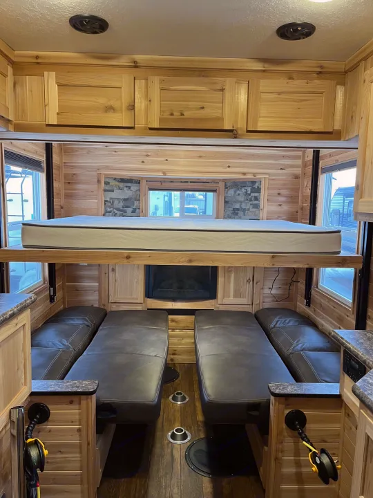 RV rental interior: A cozy ice fishing house featuring a drop-down bunk, convertible sofas, fireplace & wood paneling.. Ice Castle Fish Houses Ice Castle Fish Houses Trailer 2023