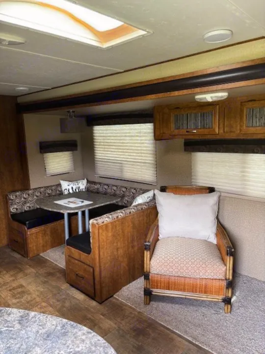 Inside this RV rental: a comfy dinette booth, a cozy armchair, and ample light from windows & a skylight.. Crossroads RV Zinger 2017