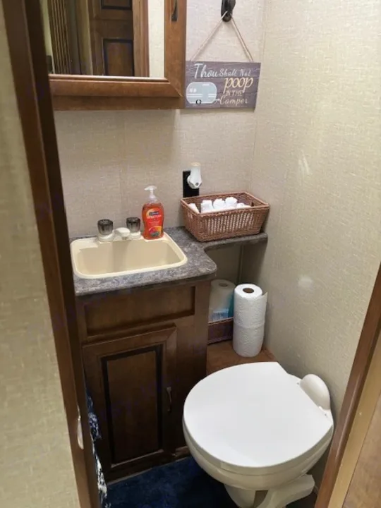 This RV rental bathroom features a compact sink, toilet, mirror, and a humorous "Thou Shall Not poop In The Camper" sign.. Crossroads RV Zinger 2017