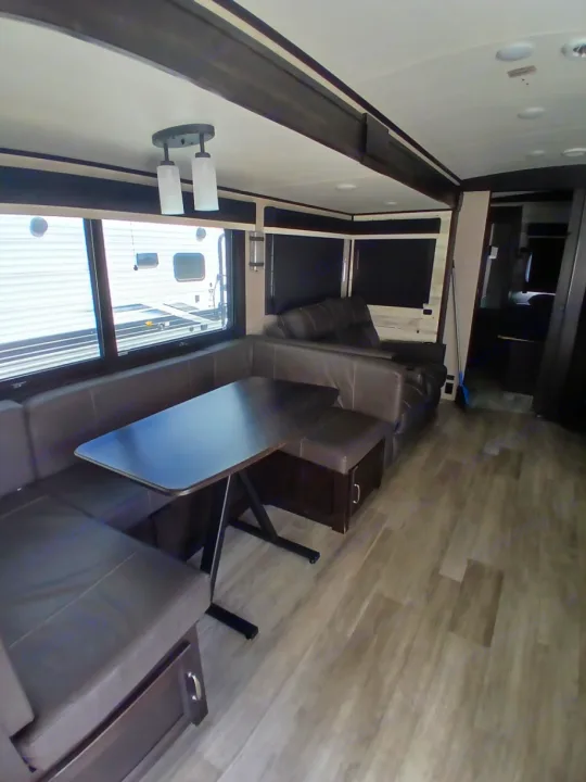 RV rental interior: brown leatherette dinette, dark table, large windows, and overhead lighting.. Jayco White Hawk 2023