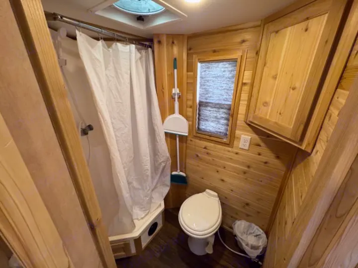 RV rental bathroom: compact wood-paneled shower & toilet. Essential amenities for your travel adventures.. Ice Castle Fish Houses Ice Castle Fish Houses Trailer 2023