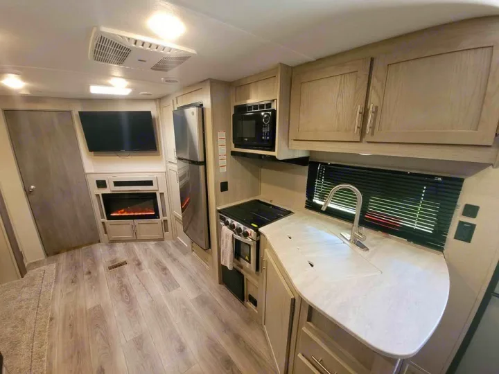Bright, modern RV rental interior with a fully equipped kitchen, TV, and fireplace. Ready for your travels!. Coachmen catalina 2022