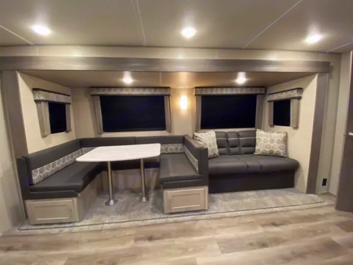 RV rental interior: cozy U-shaped dinette, comfortable sofa, and multiple windows. Ideal for travel and relaxation.. Coachmen catalina 2022