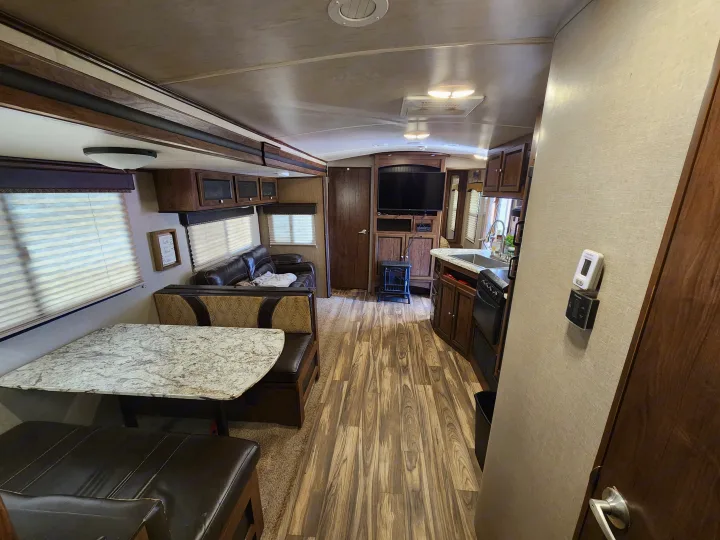 RV rental interior featuring a practical dinette, comfortable sofa, compact kitchen with wood-look flooring, and entertainment area.. Cruiser RV MPG Ultra Lite 2017
