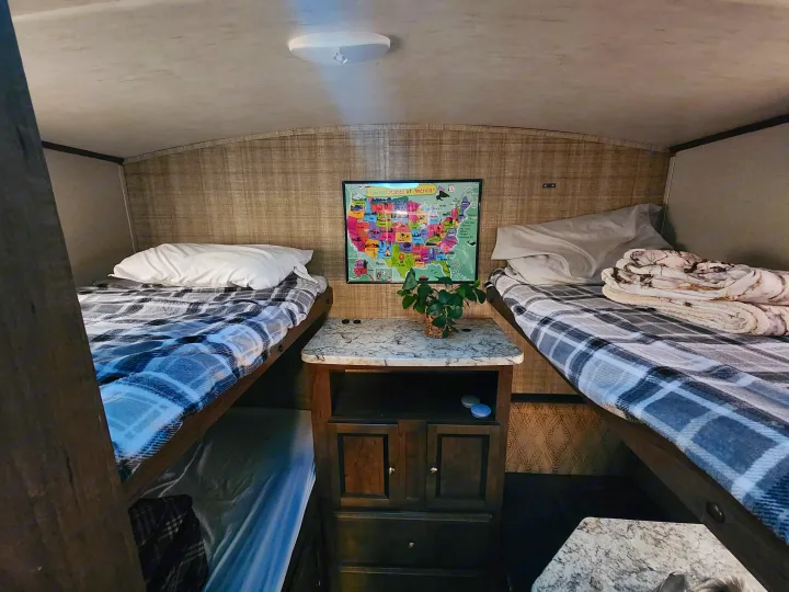 RV rental bunk beds flank a central console, adorned with a US map, creating a cozy sleeping space for travel.. Cruiser RV MPG Ultra Lite 2017