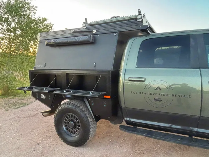 Rugged olive-green overlanding truck with a roof-top tent & utility bed, branded for La Jolla Adventure RV Rentals.. Ram Power Wagon 2020