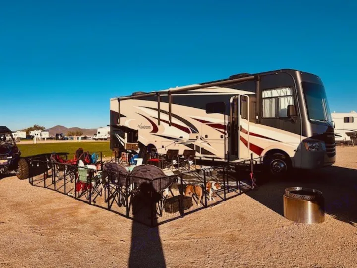 Perfect RV rental setup! A motorhome at a sunny campsite with a pet-friendly fenced outdoor living area and fire pit.. Coachmen Mirada 32SS 2019