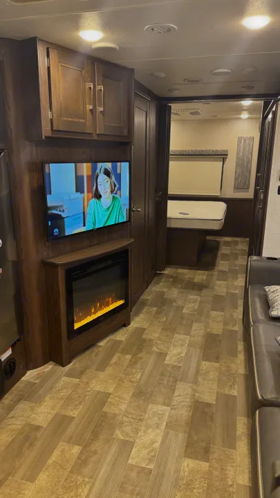 Cozy RV rental interior showing a living area with a TV, electric fireplace, and a peek into the bedroom.. Coachmen Mirada 32SS 2019