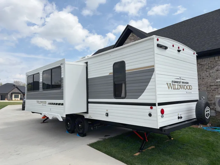 This **RV rental**, a Forest River Wildwood X-Lite travel trailer, is parked at home with its slide-out extended.. Forest River Wildwood X-Lite 273QBXL 2026