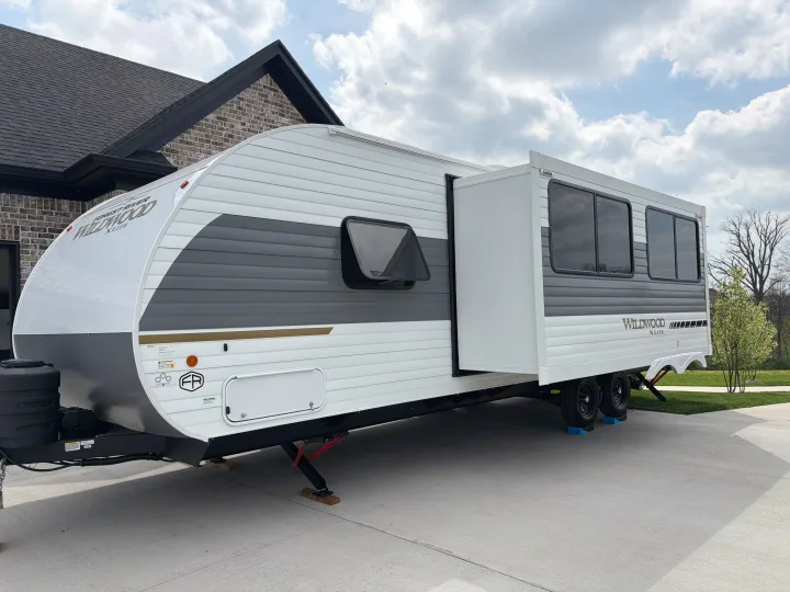 Modern Wildwood X-Lite travel trailer with slide-out extended, parked on a driveway; great for an rv rental adventure.. Forest River Wildwood X-Lite 273QBXL 2026