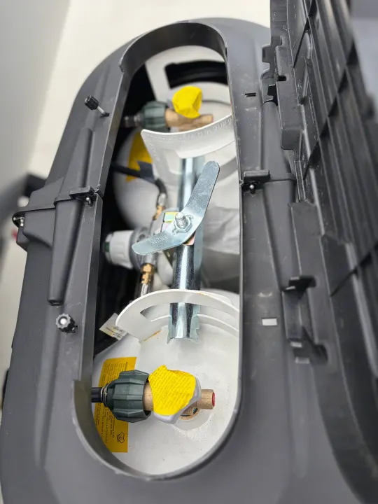 Dual propane tanks with connections visible, safely housed in a protective cover on an RV rental for gas supply.. Forest River Wildwood X-Lite 273QBXL 2026