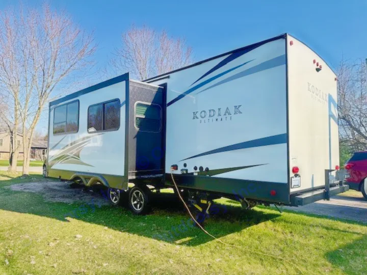 This Kodiak Ultimate travel trailer, perfect for RV rental, is parked with its slide-out extended on a sunny day.. Kodiak Ultimate 288BHSL 2018