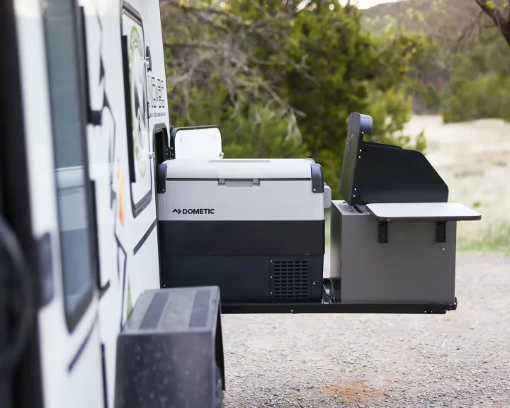 An RV rental's extended side compartment reveals a Dometic portable fridge and an outdoor grill station, ready for adventure.. No Boundaries 10 2020