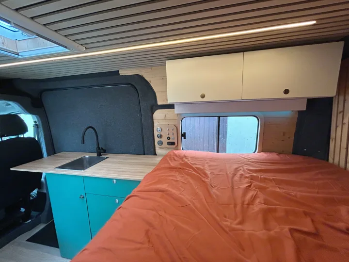 Modern rv rental: kitchen with sink, comfy bed, wood ceiling, and overhead cabinets, lit by LED strips.. FIAT Ducato 2013