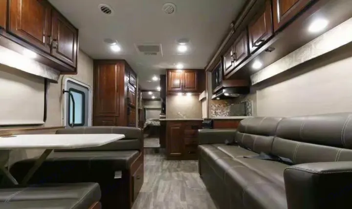 Spacious RV rental interior featuring a dinette, sofa, and kitchen with wood cabinets. Brightly lit for comfortable travel.. Forest River forester 2017