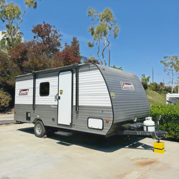 Coleman travel trailer RV rental parked on concrete with blue sky & trees, ready for your next adventure.. Coleman Lantern 17B 2024