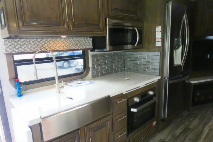 Modern kitchen in an RV rental, with stainless steel appliances, a stylish backsplash, and a deep sink.. Forest River Georgetown 2020