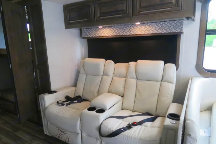Plush recliners with cup holders in an RV rental's cozy living space, featuring dark cabinets and bunk access.. Forest River Georgetown 2020