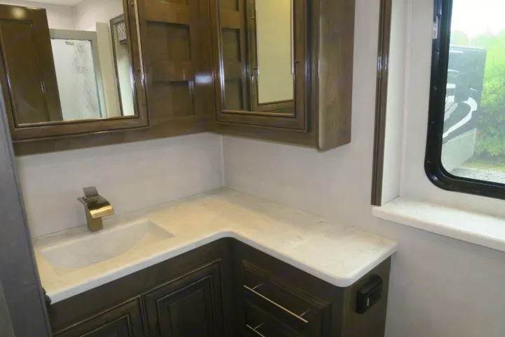 Modern rv rental bathroom with a marble-look counter, integrated sink, sleek faucet, and dark wood cabinets.. Forest River Georgetown 2020
