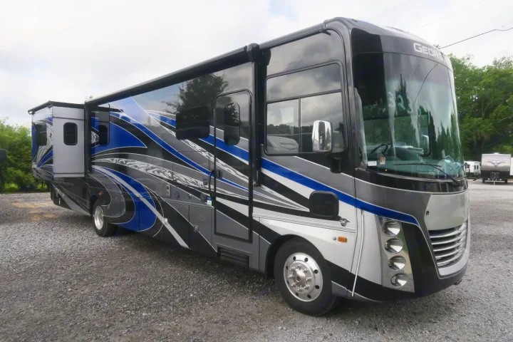 This large, colorful Georgetown motorhome, an ideal RV rental, is parked on a gravel lot, ready for adventure.. Forest River Georgetown 2020