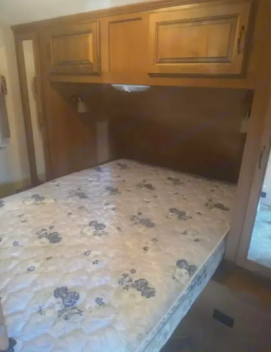 RV rental bedroom: A floral-patterned mattress under wooden cabinets with built-in lights and bedside mirrors, ready for your trip.. Cruiser RV Viewfinder Signature 2015
