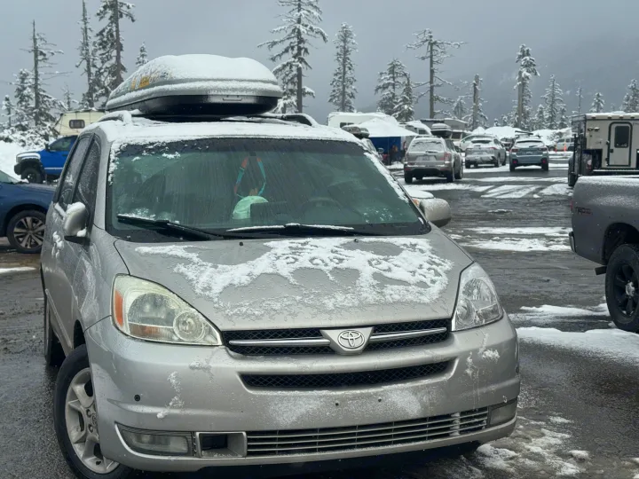 Silver minivan in a snowy lot, suggesting winter travel. RV rental and snow-covered trees highlight outdoor adventure options.. Toyota Sienna Limited XLE Camper Van 2004