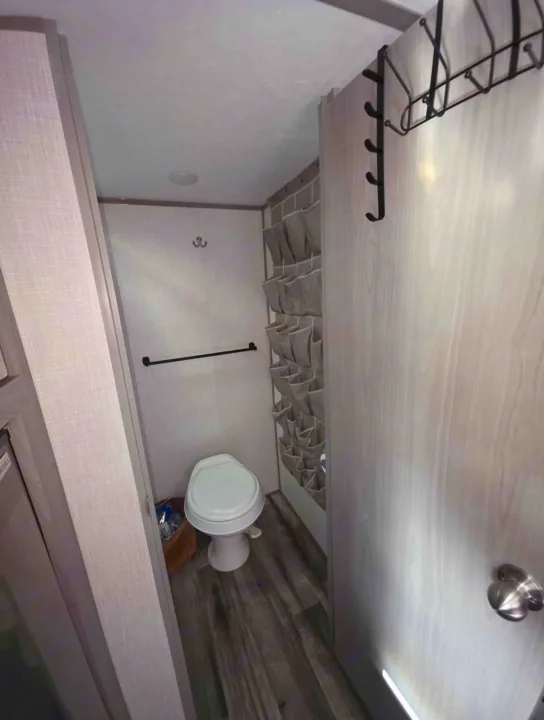 RV rental bathroom: Compact toilet, towel bar, and clever shoe/storage organizer maximizing space.. Dutchmen Coleman Lantern LT 2022