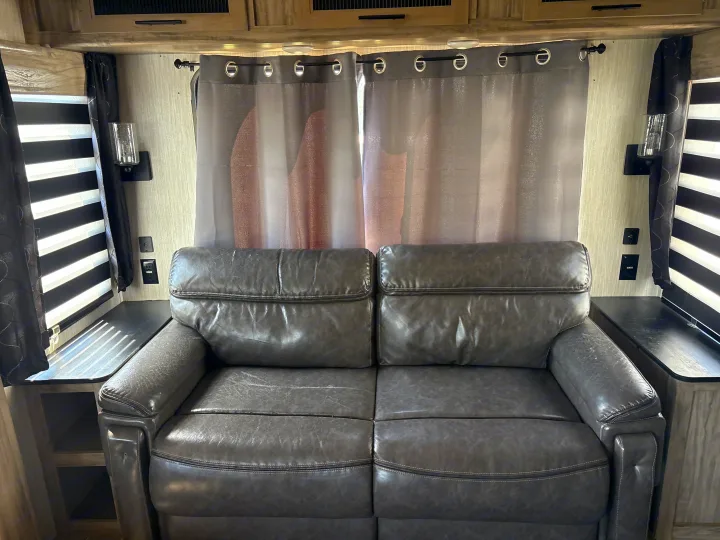 RV rental interior: Comfortable gray sofa with blinds, curtains, wall sconces, and convenient outlets for your journey.. Forest River Cherokee Alpha Wolf 2021